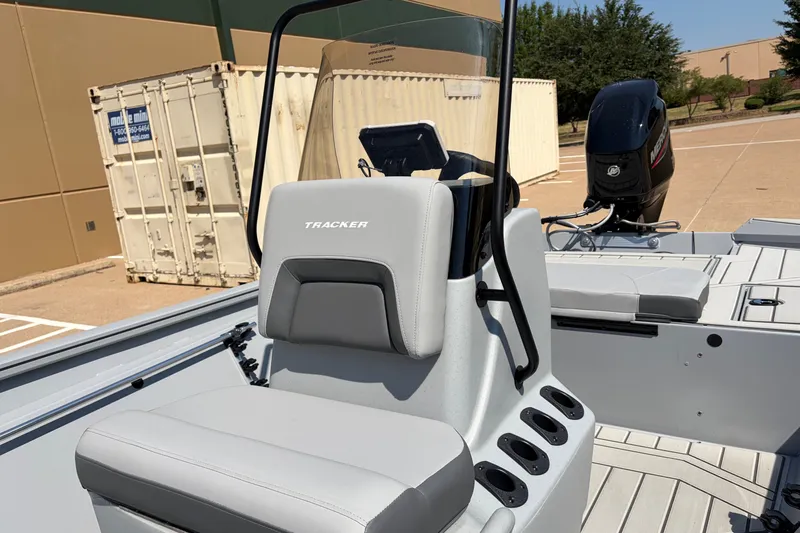 Slide: The Image of 2027 Tracker Bass Tracker 175 CC boat interior with seating and console, parked outdoors. - 14