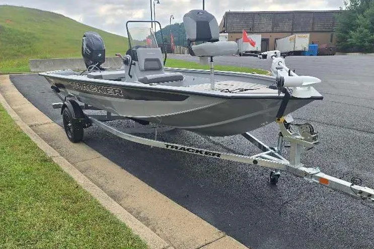 The Image of 2027 Tracker Bass Tracker 175 CC boat on trailer, parked on asphalt near grassy hill. - 0