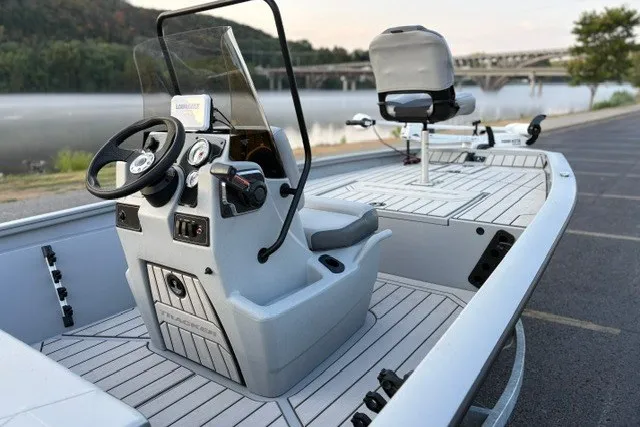 Slide: The Image of 2027 Tracker Bass Tracker 175 CC boat interior with steering console, docked by a scenic river. - 22