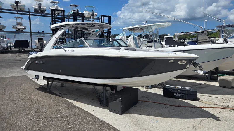 Slide: The Image of A sleek 2023 Cobalt 30SC boat on a dry dock, surrounded by other boats. - 1