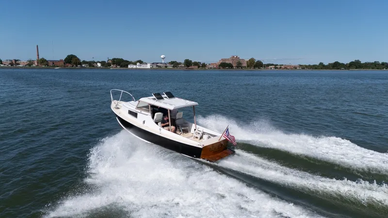 Slide: The Image of A 1959 Dyer 29 Trunk Cabin boat speeds across the water, with an American flag at the stern. - 46