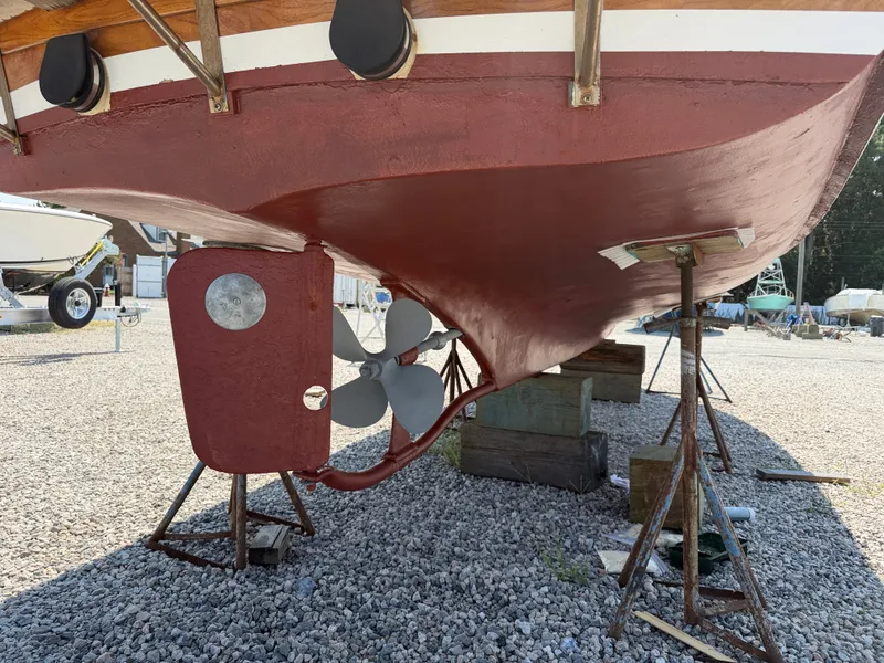 Slide: The Image of A 1959 Dyer 29 Trunk Cabin boat on a gravel lot. The hull is painted red. - 7