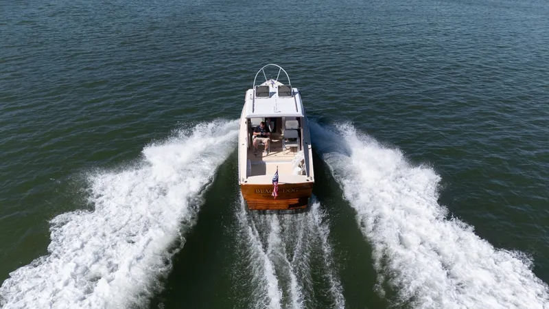 Slide: The Image of A 1959 Dyer 29 Trunk Cabin boat cruising on water, leaving a splashing wake. - 2