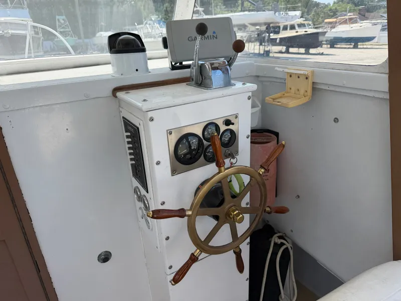 Slide: The Image of The image shows the helm of a 1959 Dyer 29 Trunk Cabin boat with a wooden steering wheel and instruments. - 14
