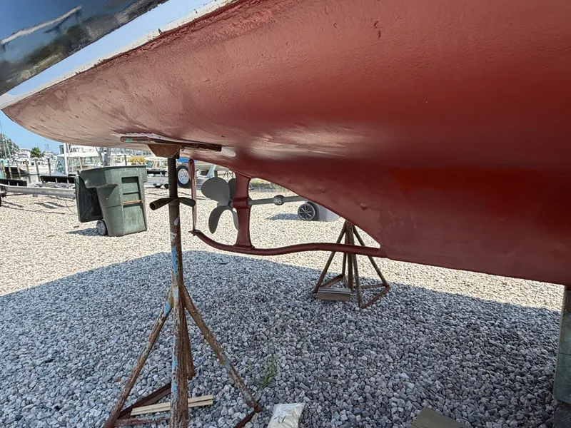 Slide: The Image of A 1959 Dyer 29 Trunk Cabin boat on a gravel lot. The hull is painted red. - 11