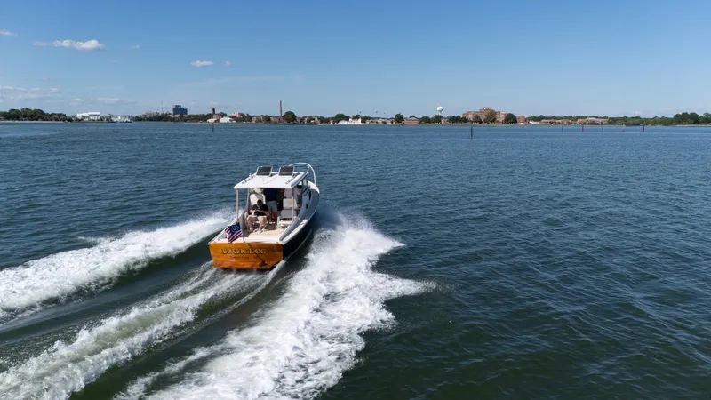 Slide: The Image of A 1959 Dyer 29 Trunk Cabin boat speeds across the water, with a cityscape in the background. - 38