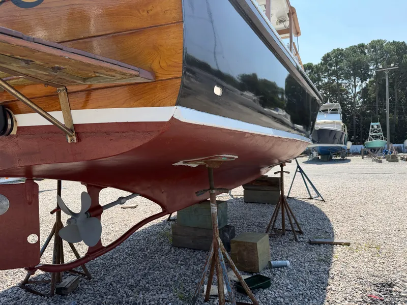 Slide: The Image of A 1959 Dyer 29 Trunk Cabin boat is on dry dock. The hull is black and red. - 8