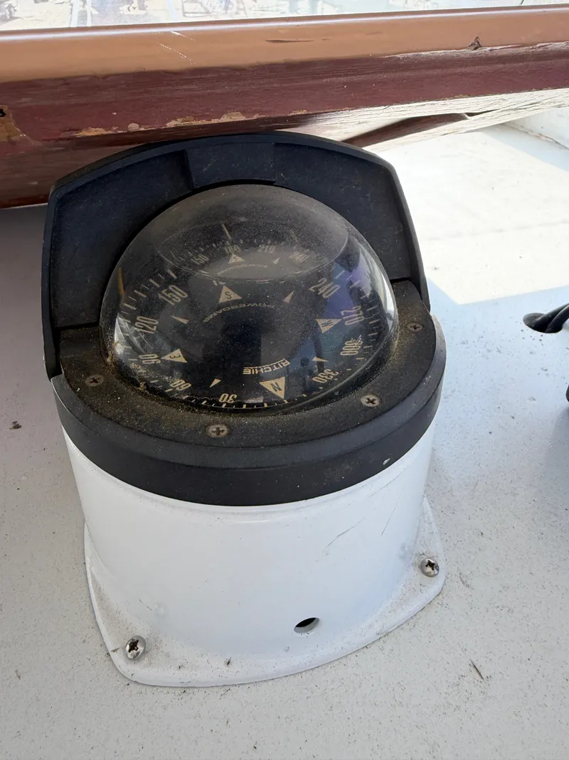 Slide: The Image of A compass on a boat, surrounded by wood and metal. - 21