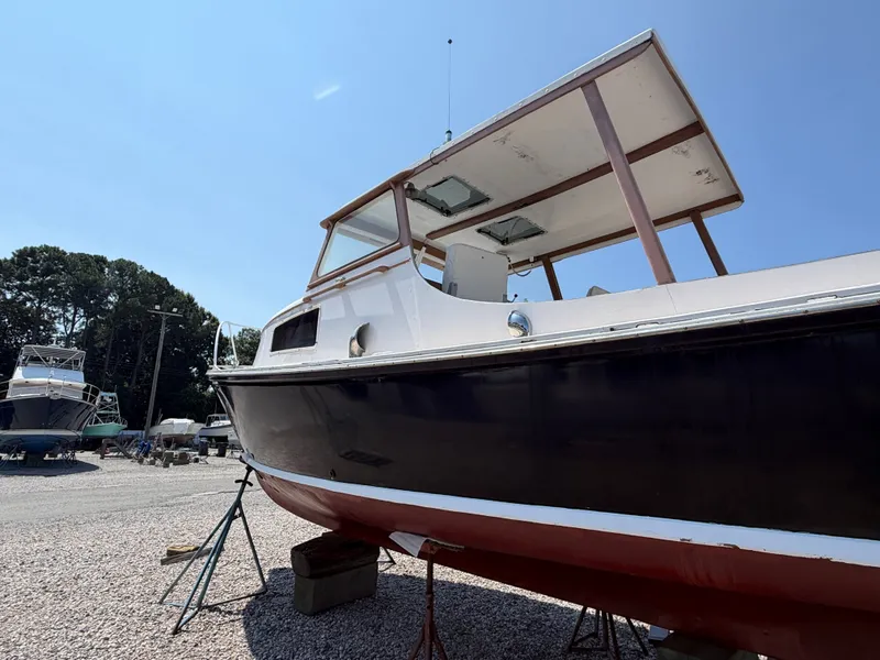 Slide: The Image of A 1959 Dyer 29 Trunk Cabin boat on a gravel lot. It features a dark blue hull. - 13