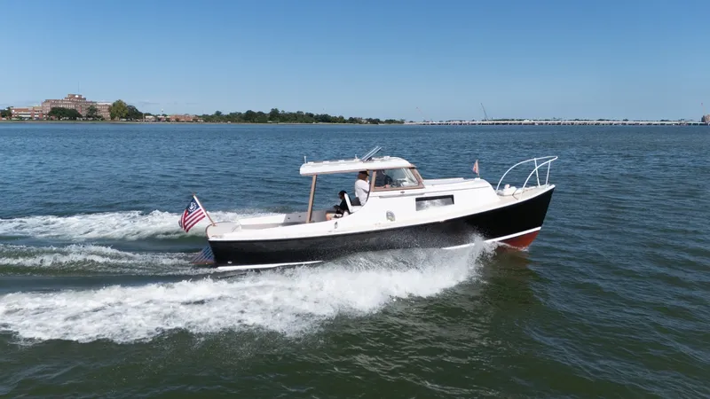 Slide: The Image of A 1959 Dyer 29 Trunk Cabin boat cruising on calm water. It features a black hull. - 4