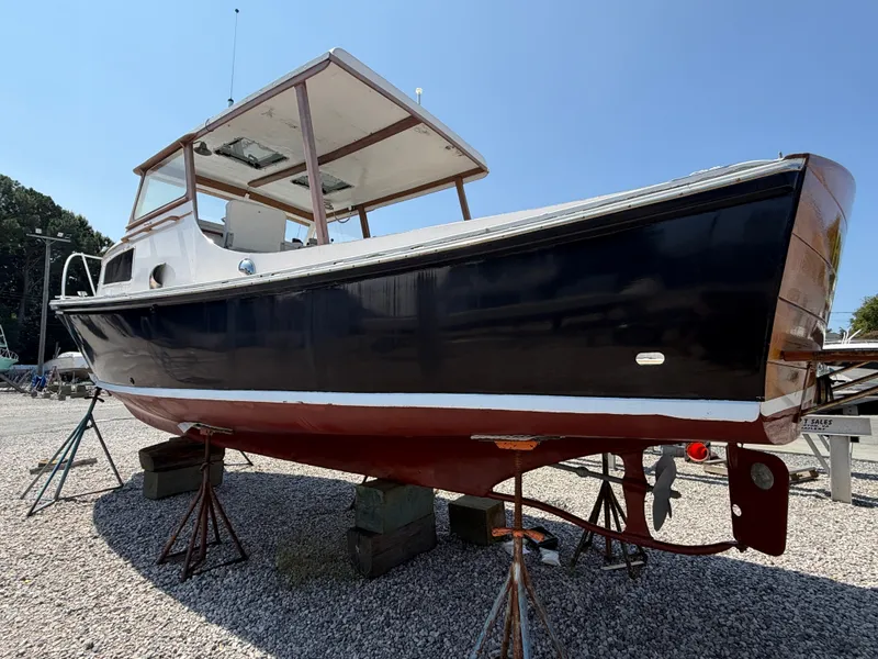 Slide: The Image of A 1959 Dyer 29 Trunk Cabin boat on a gravel lot. It features a dark blue hull. - 12