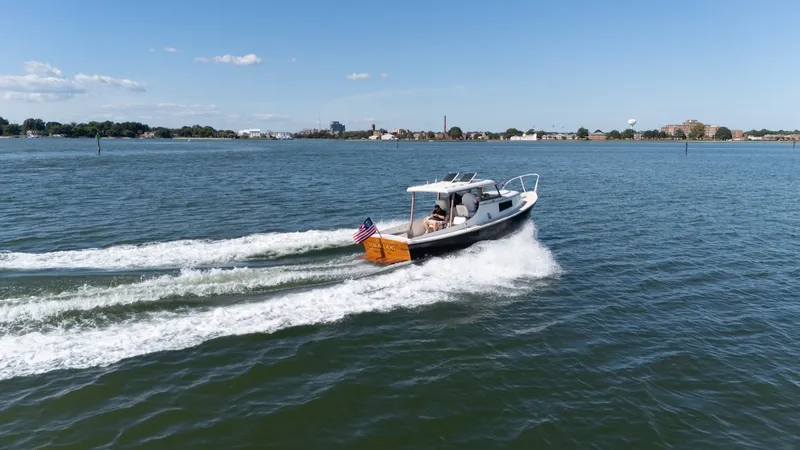Slide: The Image of A classic 1959 Dyer 29 Trunk Cabin boat speeds across the water, with an American flag at the stern. - 37