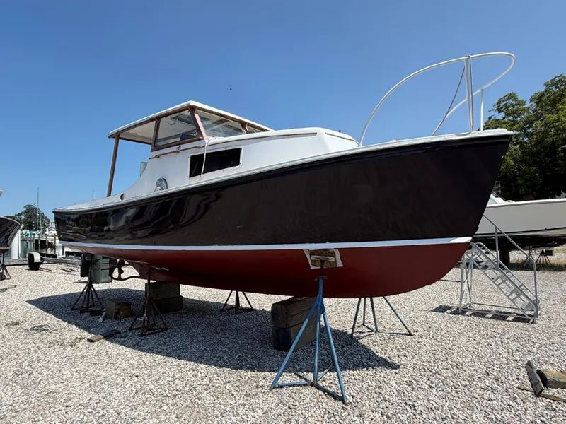 Slide: The Image of A 1959 Dyer 29 Trunk Cabin boat on a gravel lot. It features a red hull. - 10