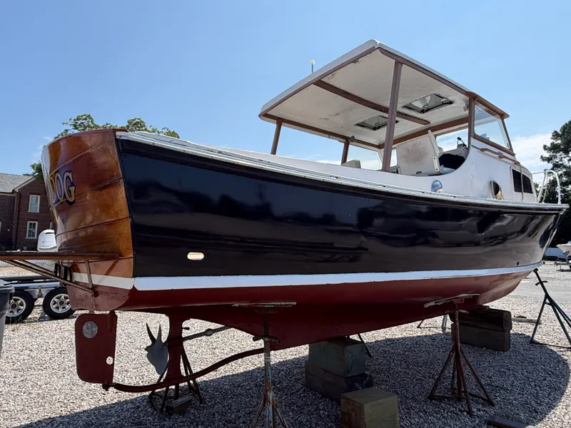 Slide: The Image of A 1959 Dyer 29 Trunk Cabin boat is on dry dock. It features a black and red paint scheme. - 9