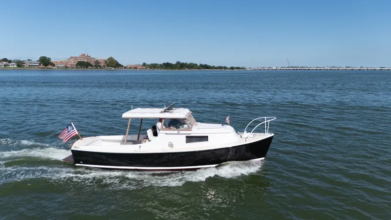 Slide: The Image of A classic 1959 Dyer 29 Trunk Cabin boat cruising on calm waters with an American flag. - 32
