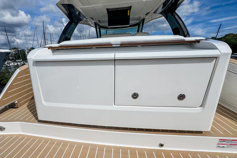 Slide: The Image of 2027 Tiara Yachts 39 LS boat deck with storage compartment, marina background. - 27