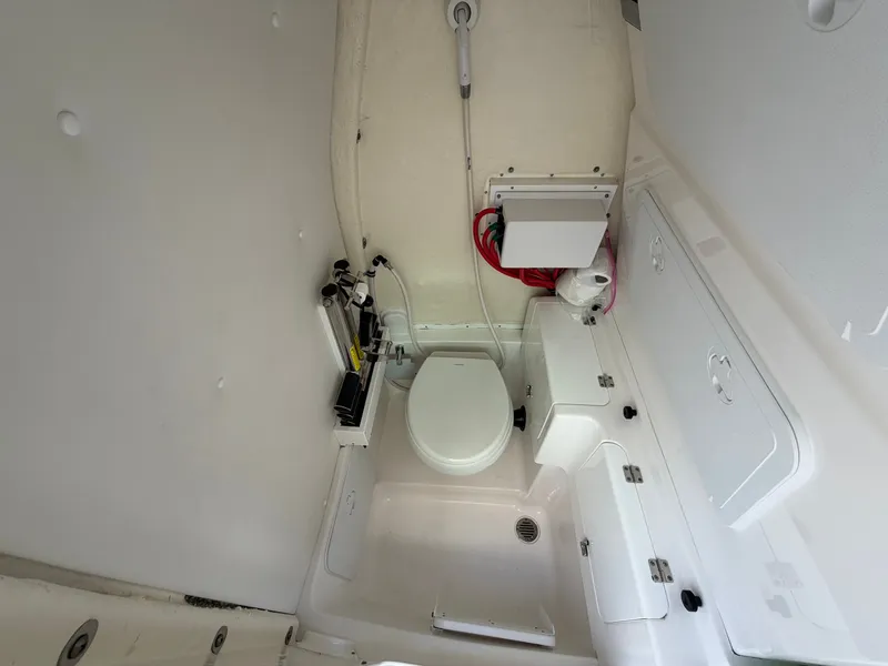 Slide: The Image of The image shows a compact boat toilet with white walls and a small sink. - 47