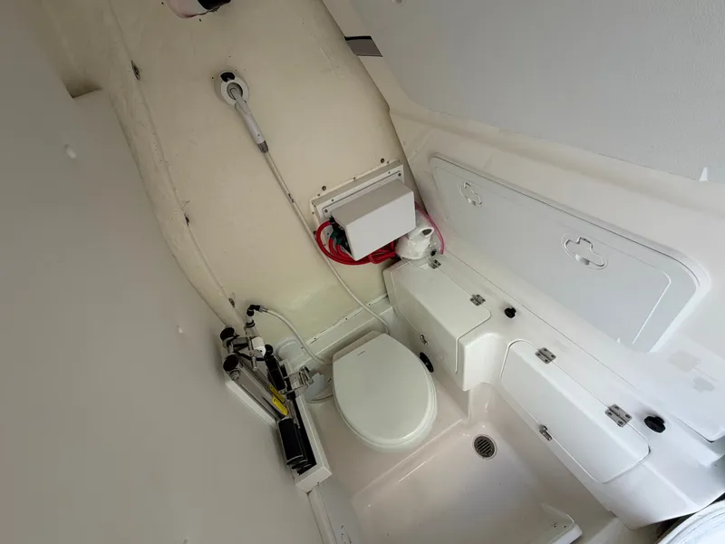 Slide: The Image of The image shows a compact boat toilet with white walls and a small sink. - 48