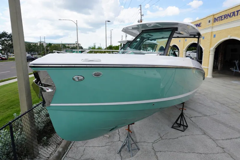 The Image of 2027 Monterey Elite 30 OB boat displayed outdoors on stands, featuring a sleek turquoise hull. - 0