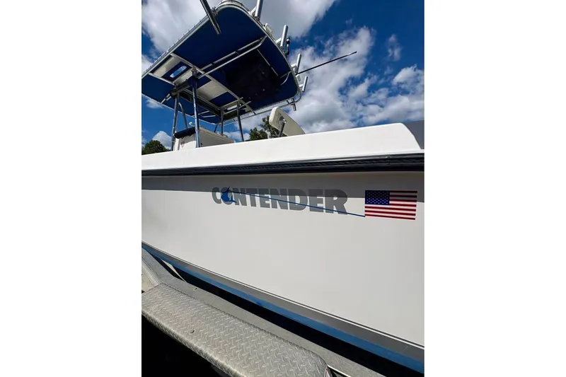 Slide: The Image of 2003 Contender 23 Open boat with American flag decal under blue sky. - 15