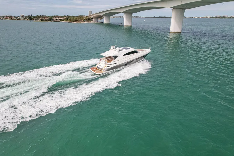 Slide: The Image of 2015 Riviera 6000 Sport Yacht cruising under a bridge on turquoise waters. - 14