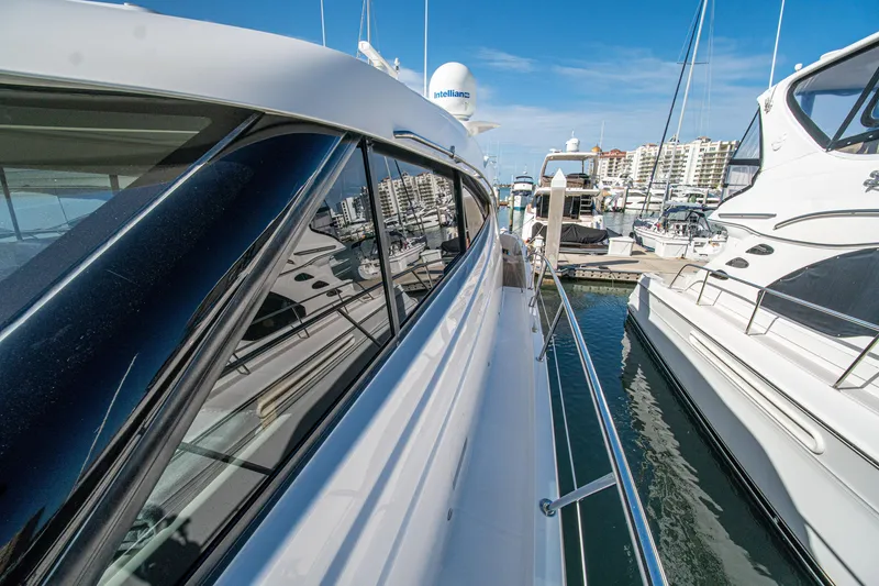 Slide: The Image of 2015 Riviera 6000 Sport Yacht docked at marina, reflecting clear blue sky and nearby boats. - 66