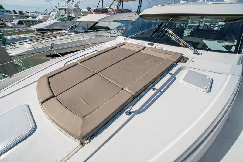 Slide: The Image of 2015 Riviera 6000 Sport Yacht with sunpad, docked among other luxury boats. - 65