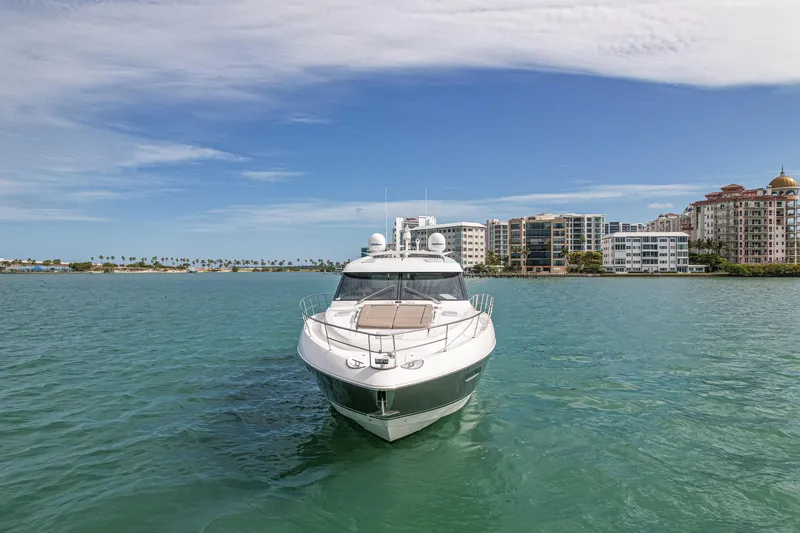Slide: The Image of 2015 Riviera 6000 Sport Yacht on serene water with cityscape background. - 4