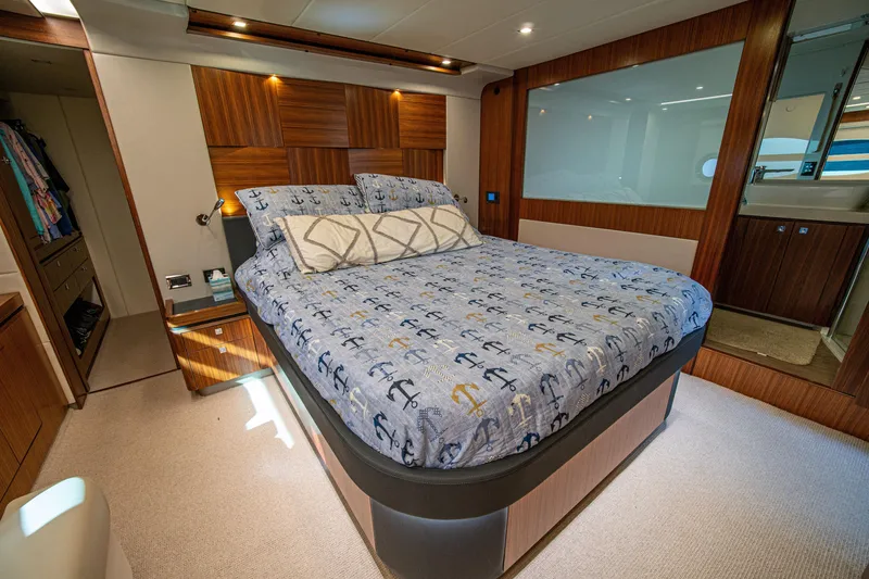 Slide: The Image of Luxurious 2015 Riviera 6000 Sport Yacht bedroom with anchor-themed bedding and elegant wood paneling. - 50