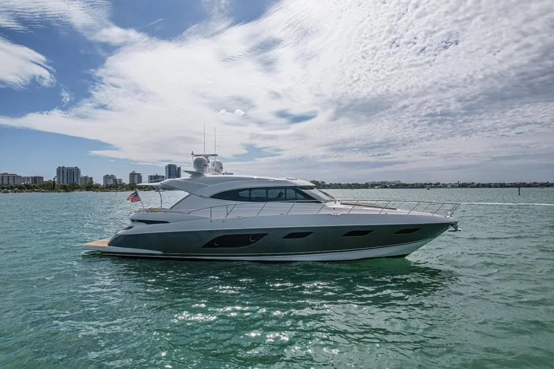 Slide: The Image of 2015 Riviera 6000 Sport Yacht cruising on a sunny day with city skyline backdrop. - 7