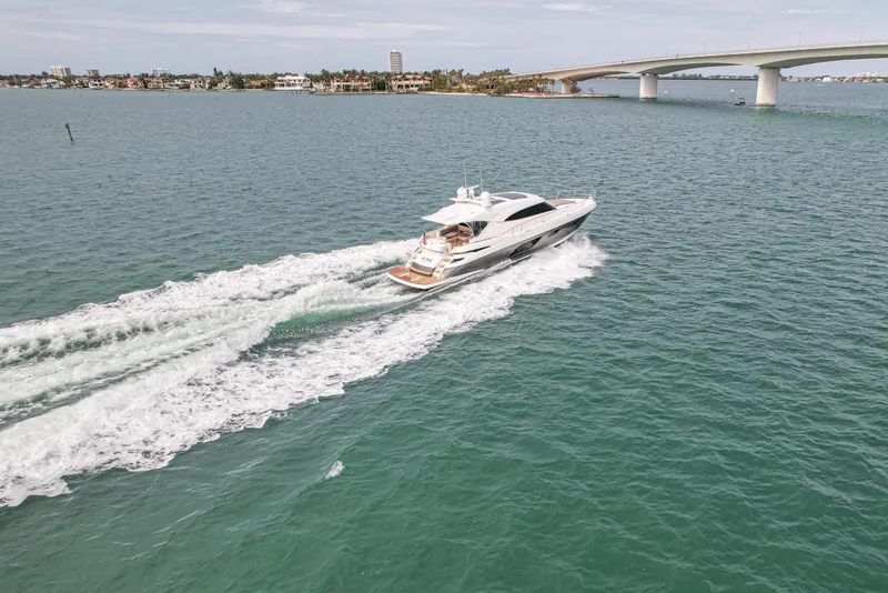 Slide: The Image of 2015 Riviera 6000 Sport Yacht cruising on open water near a bridge. - 13