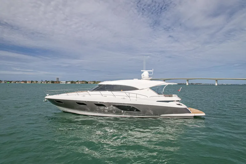 Slide: The Image of 2015 Riviera 6000 Sport Yacht cruising on open water under a partly cloudy sky. - 2