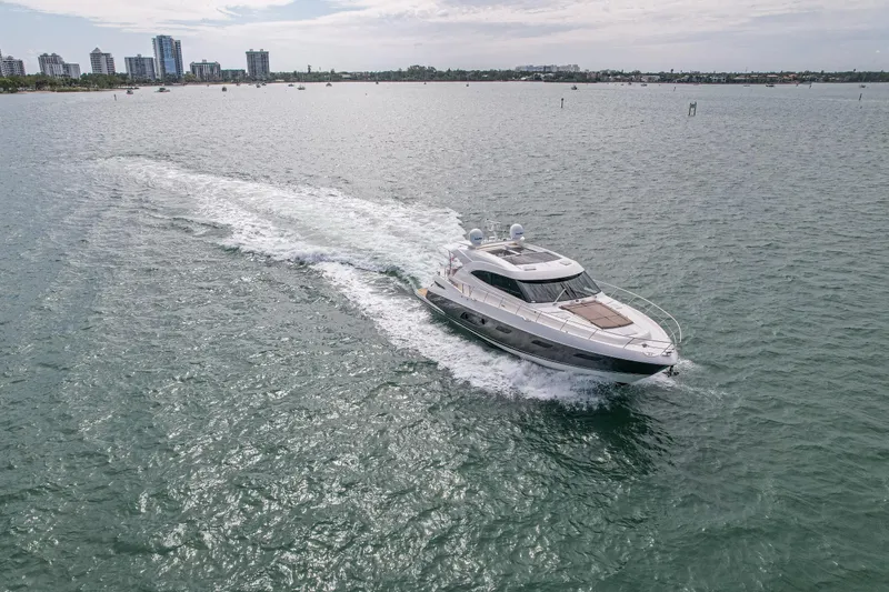 Slide: The Image of 2015 Riviera 6000 Sport Yacht cruising on open water near city skyline. - 12