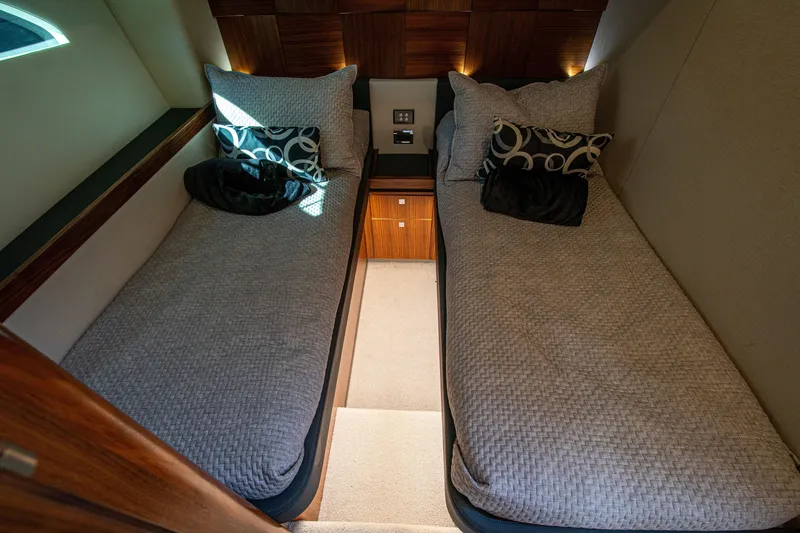 Slide: The Image of Luxurious twin cabin interior of 2015 Riviera 6000 Sport Yacht, featuring elegant bedding and wood accents. - 44