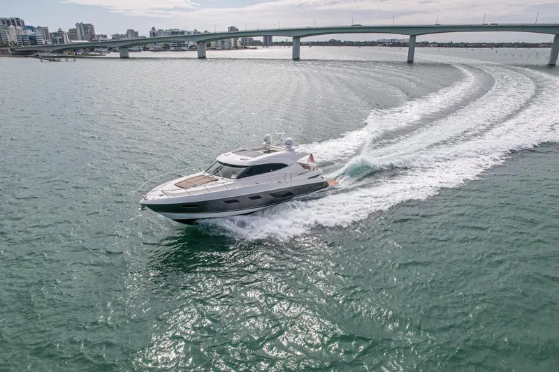 Slide: The Image of 2015 Riviera 6000 Sport Yacht cruising under a bridge on a sunny day. - 15
