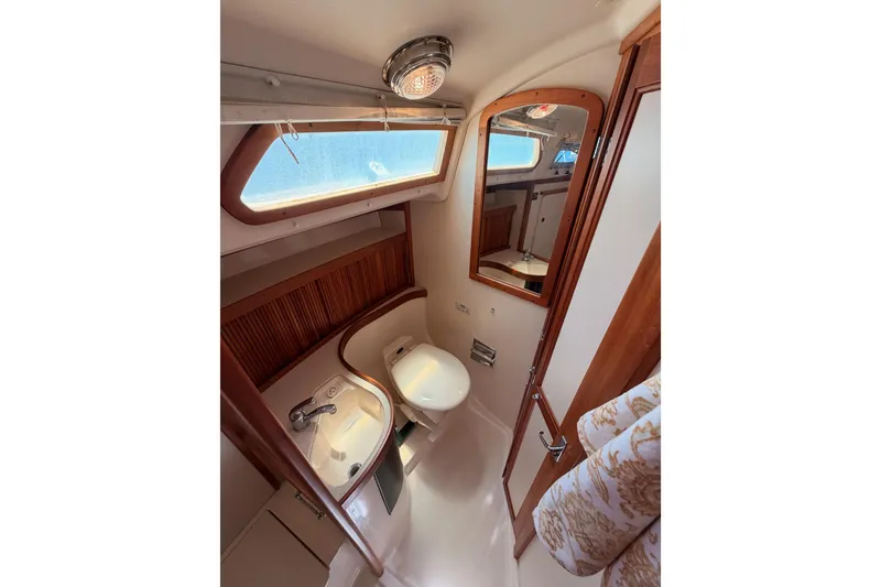 Slide: The Image of 2002 Sabre 362 yacht bathroom with sink, toilet, mirror, and wooden accents. - 60