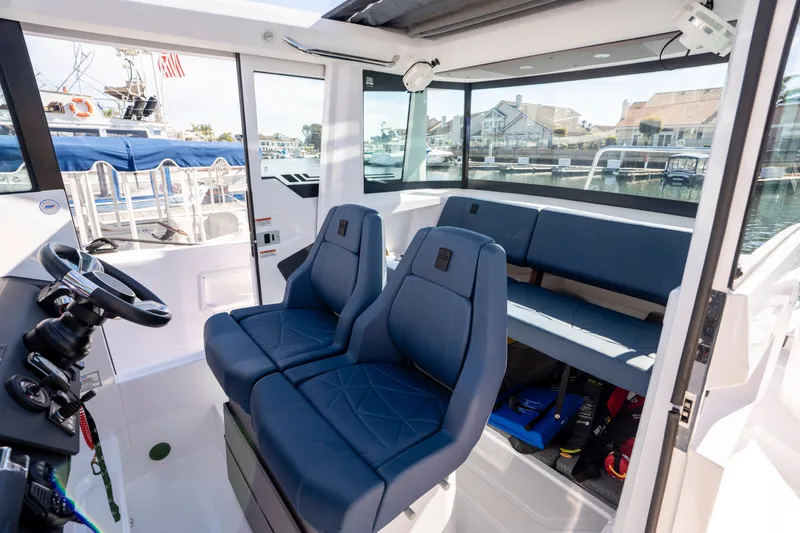 Slide: The Image of 2024 Axopar 29 XC Cross Cabin interior with blue seating and modern helm. - 9