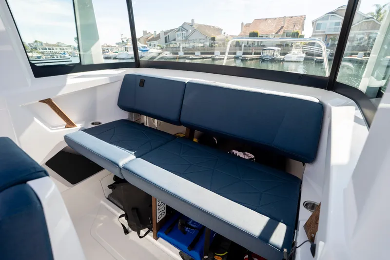 Slide: The Image of 2024 Axopar 29 XC Cross Cabin interior with blue seating and waterfront view. - 10