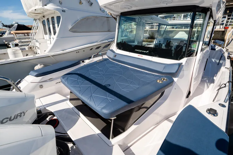 Slide: The Image of 2024 Axopar 29 XC Cross Cabin boat with blue seating, docked at marina. - 5