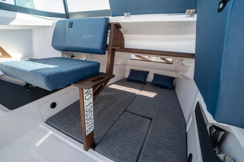 Slide: The Image of 2024 Axopar 29 XC Cross Cabin interior with blue seating and cozy sleeping area. - 11