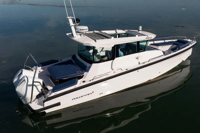 Slide: The Image of 2024 Axopar 29 XC Cross Cabin boat on calm water, showcasing sleek design and modern features. - 2