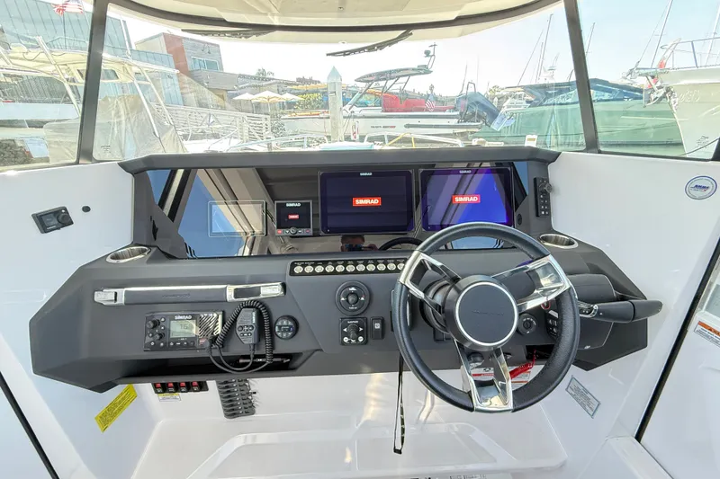 Slide: The Image of 2024 Axopar 29 XC Cross Cabin helm with modern navigation displays and steering wheel. - 15