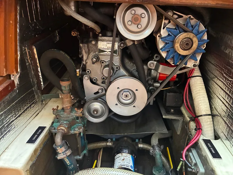 Slide: The Image of The engine compartment of a 1988 Pearson 33-2 shows a well-maintained engine with hoses and belts. - 47