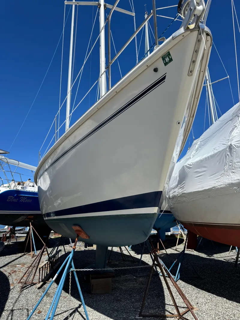 Slide: The Image of A 1988 Pearson 33-2 sailboat is on a stand. The hull is white with blue stripes. - 48