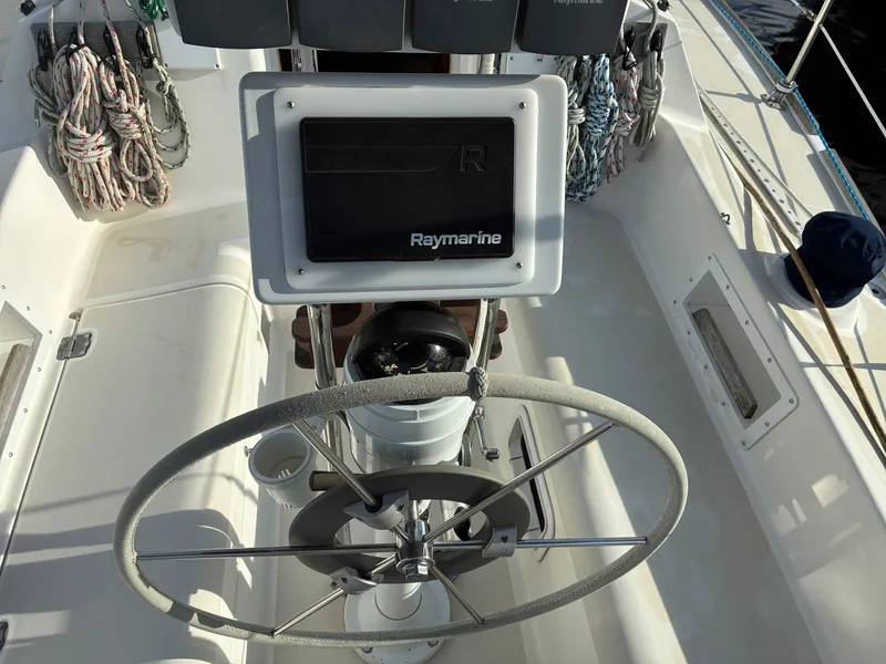 Slide: The Image of The image shows the cockpit of a 1988 Pearson 33-2 with a steering wheel and Raymarine equipment. - 15
