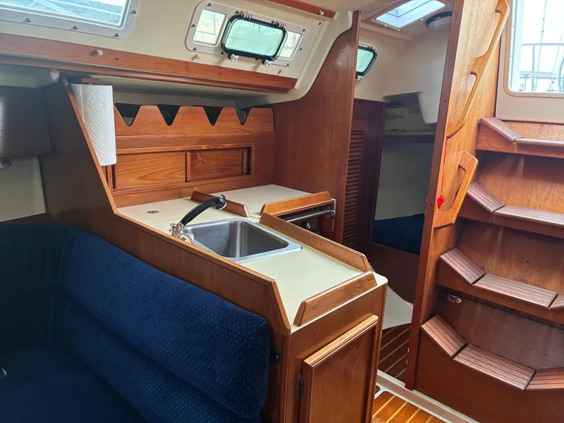 Slide: The Image of Interior of a 1988 Pearson 33-2 with wood finish, sink, and blue upholstery. - 33