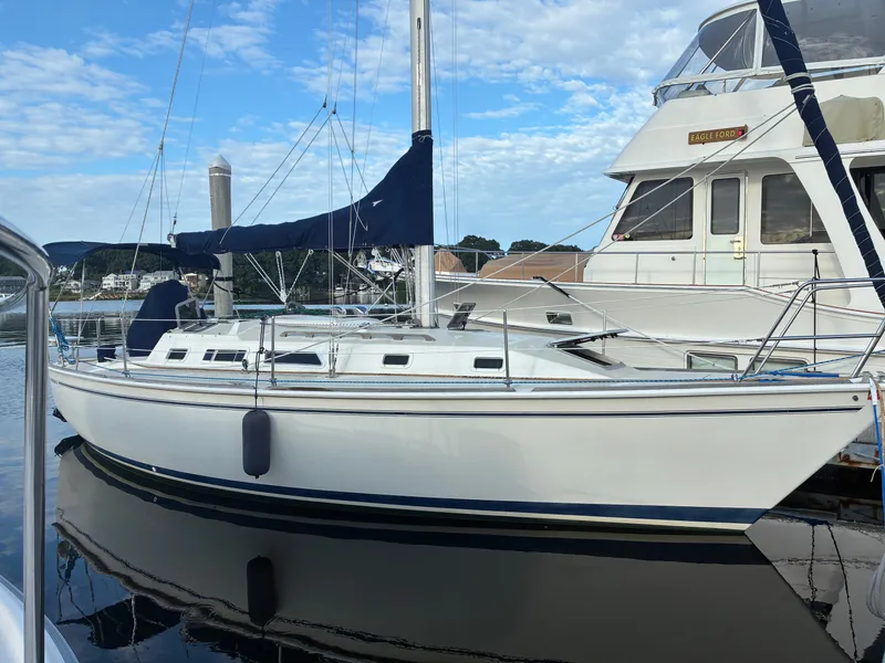 Slide: The Image of A white sailboat docked, featuring blue covers and a clear sky backdrop. - 1