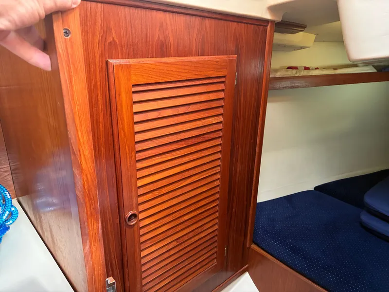 Slide: The Image of A wooden cabinet with a louvered door in a boat cabin, next to a cushioned bed. - 38