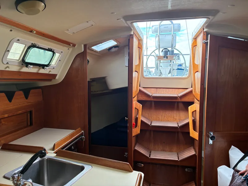 Slide: The Image of Interior of a 1988 Pearson 33-2 with wood finish and a small galley. - 34