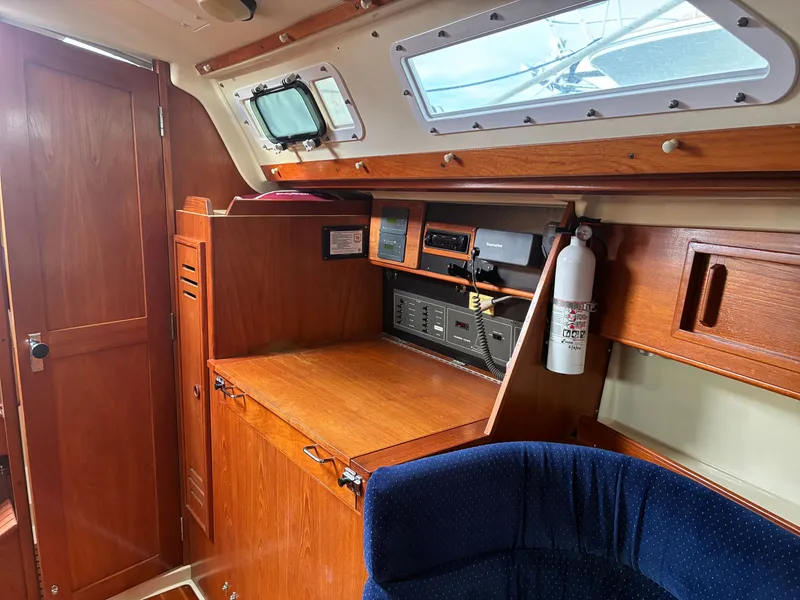 Slide: The Image of The interior of a 1988 Pearson 33-2 features wooden cabinetry, a navigation area, and a blue chair. - 28